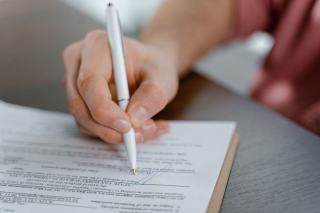 Relire les clauses d'un contrat d'édition Un contrat d'édition posé sur une table, annoté au crayon