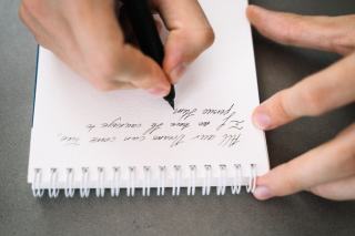 Carnet ouvert et stylo posés sur une table de travail, page à moitié remplie